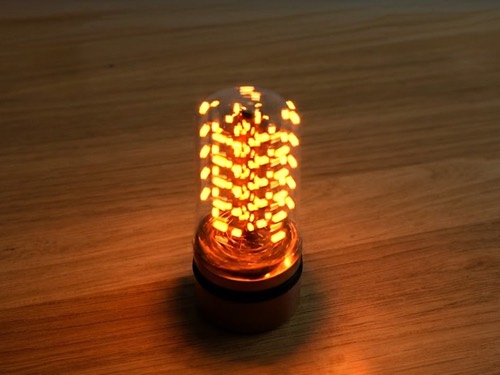 Handmade LED candle glowing under a glass dome
