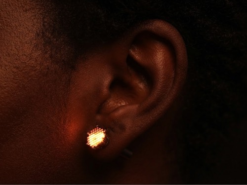 Glowing LED earring worn on an ear
